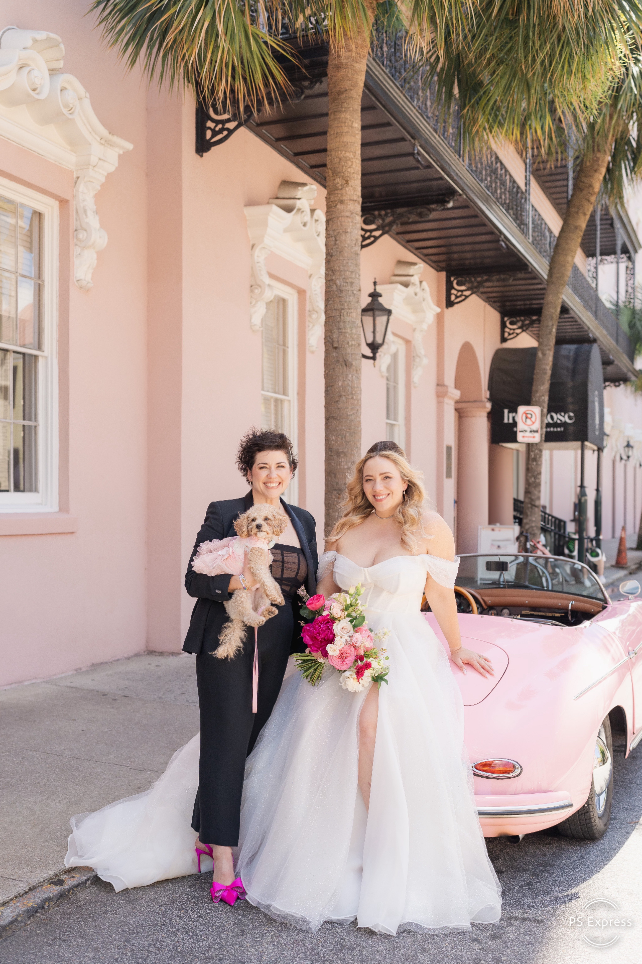 Warren and Lisa on their wedding day, posing with their dog in front of a pink vintage car
